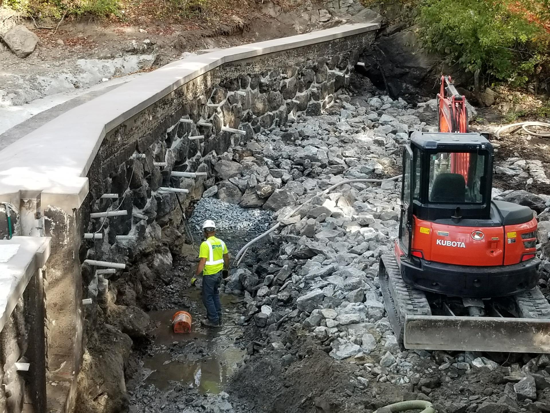 Excavating material along the downstream toe of the dam for the placement of the filter and scour protection soil media